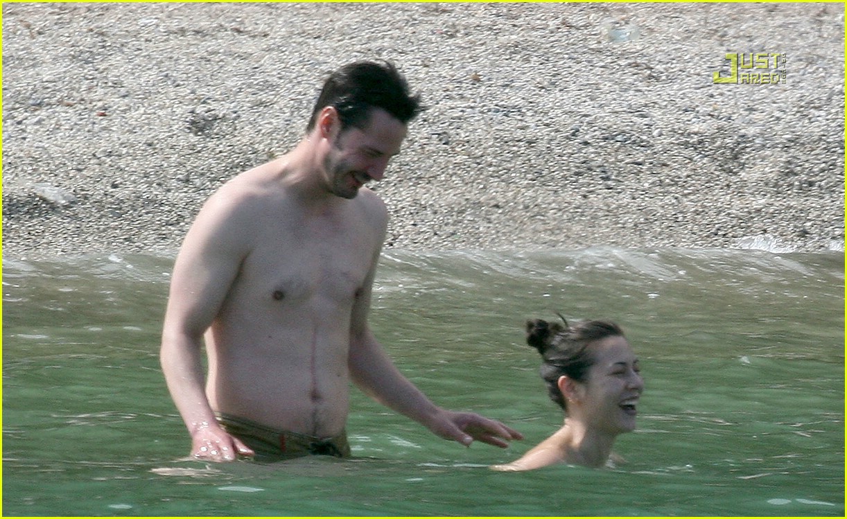 Keanu Reeves and topless female friend China Chow wade in the water togethe...
