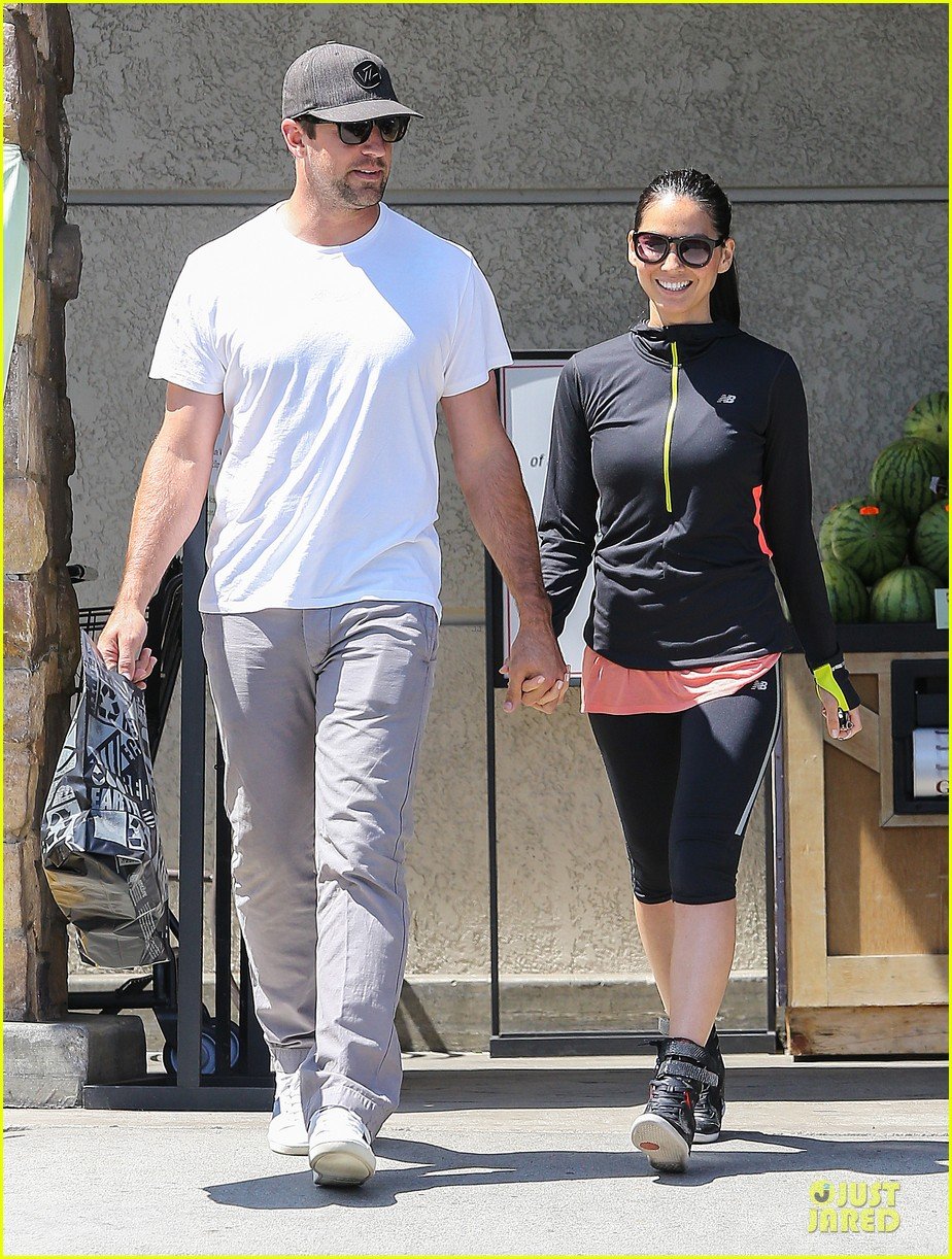 Olivia Munn and her new boyfriend Aaron Rodgers hold hands while stocking u...