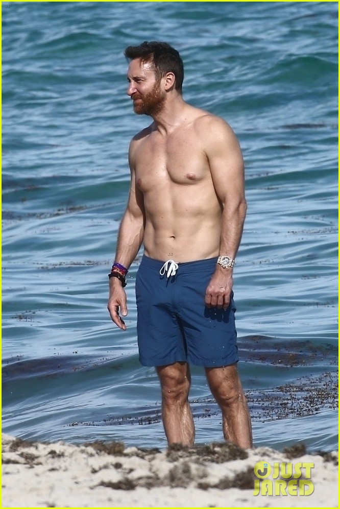 David Guetta shows off his ripped physique while going shirtless at the bea...